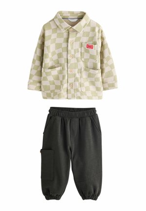 Tenue d'enfant composée d'une chemise à carreaux verts et blancs avec poches avant, et d'un pantalon de jogging noir à taille élastique avec poche latérale.