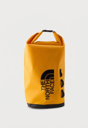 Sárga tekercses tetejű vízálló zsák fekete alappal és fekete "The North Face" logóval az elején, három fekete oldalsó hurokkal.