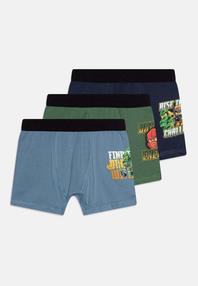 Három pár fiú boxer alsónadrág kék, zöld és tengerészkék színben, fekete derékrésszel; mindegyik különböző grafikus mintákkal és élénk színekkel rendelkezik.
