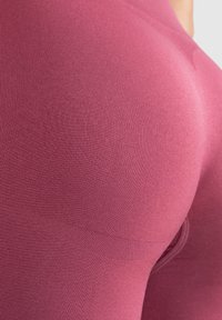 Hoge taille roze legging met een geribbelde textuur, een aansluitend ontwerp en een gladde afwerking, met een close-up van de stofdetails.