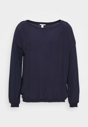 Laine pitkähihaine tummansininen paita joustavilla hihansuilla ja helmalla, pyöreä pääntie, esiteltyä yksinkertaisella valkoisella taustalla.