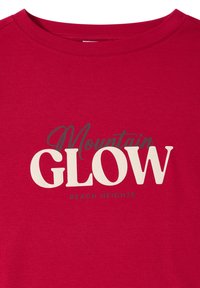 Červené bavlněné tričko s kulatým výstřihem a grafickým potiskem, který zní "Mountain GLOW REACH HEIGHTS" v různých stylech písma a barvách.
