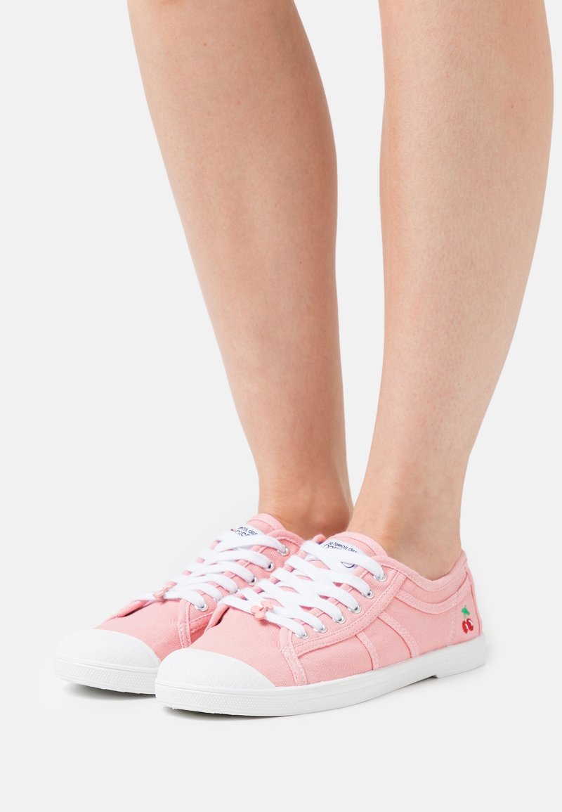 Růžové plátěné tenisky s bílými tkaničkami, bílou gumovou podrážkou a malou výšivkou třešně na boku. Nízký design s kulatou špičkou.