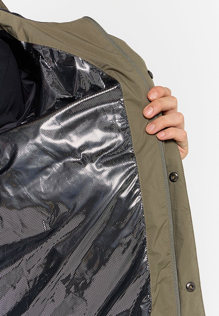 Veste vert olive avec une doublure intérieure noire métallisée, présentant une texture lisse et des boutons-pression sur le devant.