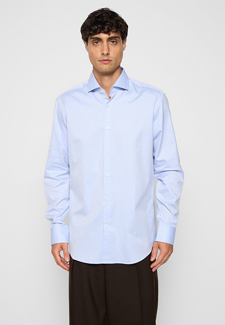 Lichtblauw langärmlig shirt van gestructureerde stof, met een knoopsluiting aan de voorkant, een puntige kraag en met manchetjes.
