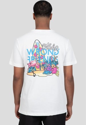 Camiseta de algodón blanca con un diseño gráfico colorido de flores tropicales, un flamenco y tablas de surf con el texto "Aloha" y "WRONG".