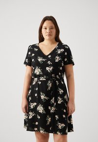 Sort svart blomstret kjole med korte ermer og V-hals. Har et belte i livet og en flytende skjør, prydet med små rosa og hvite blomster.