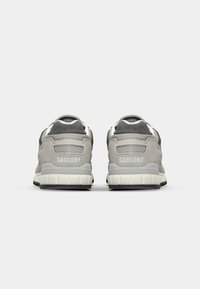 Baskets de sport grises et noires avec une tige en mesh et en suède, dotées d'un col rembourré et d'un logo blanc sur le talon. Semelle extérieure texturée.