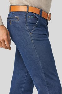 Dark blue denim jeans with a slim fit, featuring a brown leather belt and contrasting stitching. Includes front pockets and logo detail.
