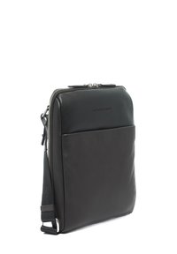Borsa per laptop in pelle nera con una texture liscia, chiusura con zip e tasca frontale. Presenta una tracolla regolabile e un design minimalista.