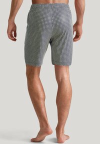 Men's swimming shorts in navy with a geometric white and green print. Made of lightweight fabric, featuring an elastic waistband and short length.