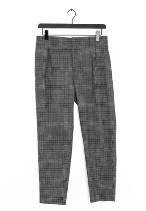 Grijze geruite, op maat gemaakte broek hangend aan een zwarte hanger tegen een witte achtergrond.