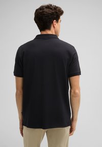 Schwarzes Poloshirt mit kurzen Ärmeln, Kragen und geradem Saum. Glatte Textur, schlichtes Design und keine sichtbaren Logos oder Muster.