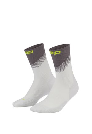Pair of white athletic socks with gray cuffs and neon yellow brand text on the top edge, showing textured knit for breathability and support.