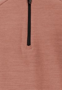 Pulloveri pehmeast, tekstureeritud roostepruuni kangast. Omab keskel musta tõmblukku ja poolkaela disaini.