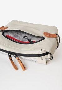 Beige etui met ritssluiting, zwarte hardware, leren accenten en een interieur met ruitjespatroon. Het heeft dubbele ritstrekkers en een lus.