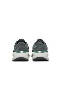 Zapatillas deportivas con parte superior de punto gris texturizado, detalles en verde y entresuela blanca. Presentan un talón redondeado y una suela exterior negra y duradera.