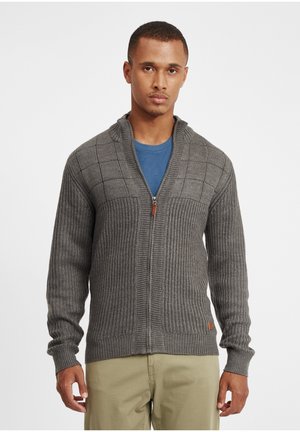 Gray knitted cardigan with a zip closure, featuring a ribbed texture and checker pattern on the chest, paired with a blue T-shirt underneath.