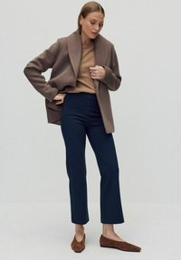 Bruine wolblend jas, beige top, navy cropped broek en bruine suède ballerina's. Gladde stof, oversized kraag, getailleerde silhouet, eenvoudig ontwerp.