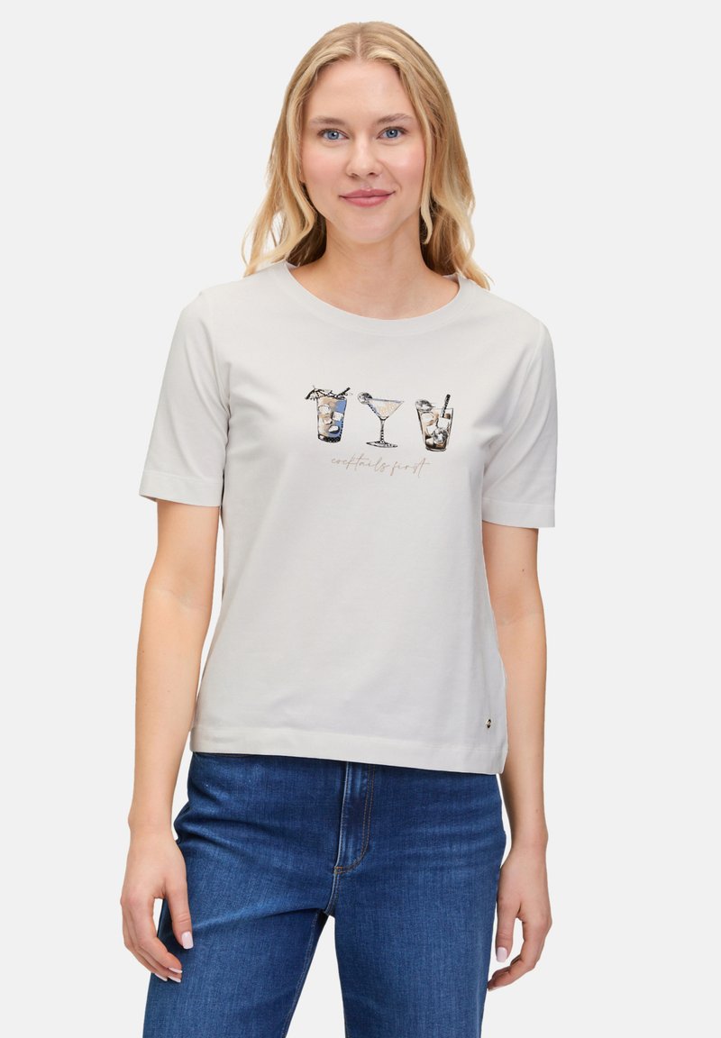 T-shirt gris clair à manches courtes avec un motif imprimé de verres à cocktail et le texte "cocktails d'abord." Matière en coton douce.