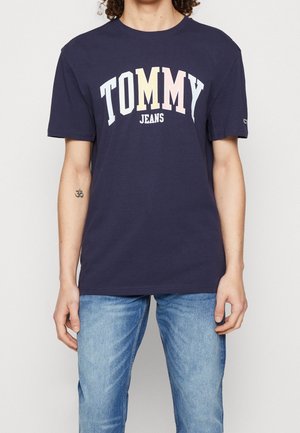 Navy blue cotton T-shirt featuring a large printed "TOMMY" logo in white, yellow, and pink, with "JEANS" in smaller white font below.