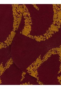 Bordeauxrote Socken mit gelbem abstraktem Muster, die eine glatte Strickstruktur aufweisen und an Zehen- und Fersenbereich für eine erhöhte Haltbarkeit verstärkt sind.