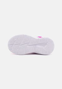 Suela de zapatilla blanca con patrones de estrellas, corazones y rayos grabados en el dibujo, mostrando el nombre de la marca Skechers.