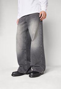 Baggy grå jeans i denim med blekta detaljer, tillverkade av mjukt tyg, med lös passform och synliga sömmar. Bärs med svarta skor.