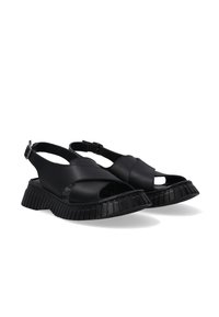 Zwarte sandalen van leer met een open teenontwerp, voorzien van een dikke gegroefde zool en een verstelbare band bij de enkel.