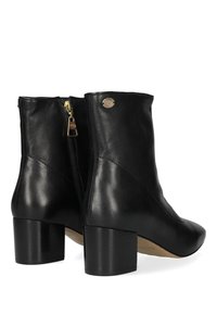 Botas de tobillo de cuero negro con punta redonda, detalle de cremallera dorada y tacón bloque. Textura suave con un brillo sutil. Placa de logo en el lateral.