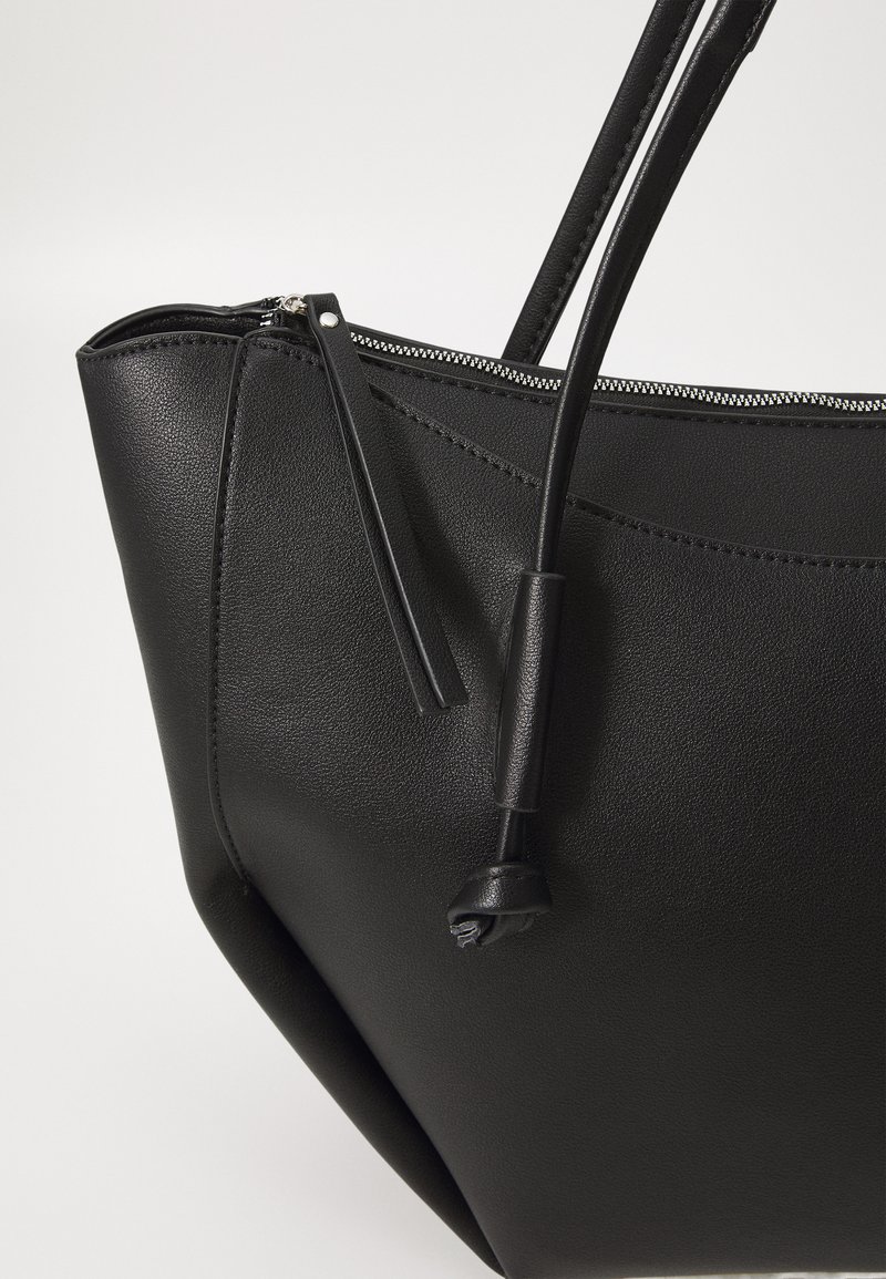 Svart läder tote-väska med dragkedjestängning, elegant design, texturerad yta och långa, hållbara remmar för bärande.