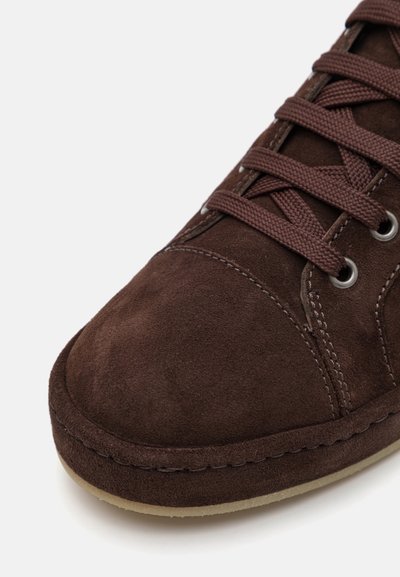 Sneakers en daim marron avec des lacets ton sur ton, bout arrondi, accents de couture et semelle en caoutchouc légère. Texture lisse avec une finition mate.