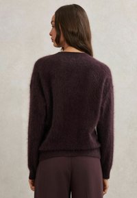 Chlpatý tmavo fialový sveter s dlhými rukávmi a okrúhlym výstrihom, s voľným strihom a jemným, štruktúrovaným povrchom.