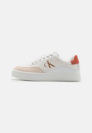 Baskets blanches avec des accents beige clair et corail. Elles présentent une tige en cuir lisse, un bout rond et une semelle en caoutchouc texturé. Logo sur le côté.