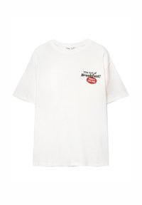 Bílý krátký rukáv T-shirt s černým textem "Umění snídaně!" a červeným štítkem s nápisem "Vitamin C & Carbs, prosím" na hrudi.