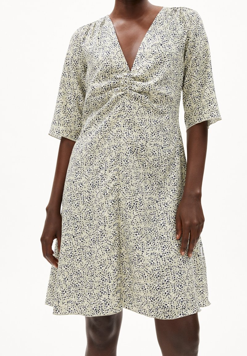 Robe à imprimé floral en crème clair avec des accents bleu marine, col en V et manches trois-quarts, avec un détail noué froncé à l'avant.
