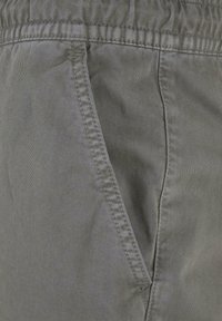 Szare szorty z tkaniny o gładkiej fakturze, wyposażone w boczną kieszeń oraz elastyczny pas dla większego komfortu.