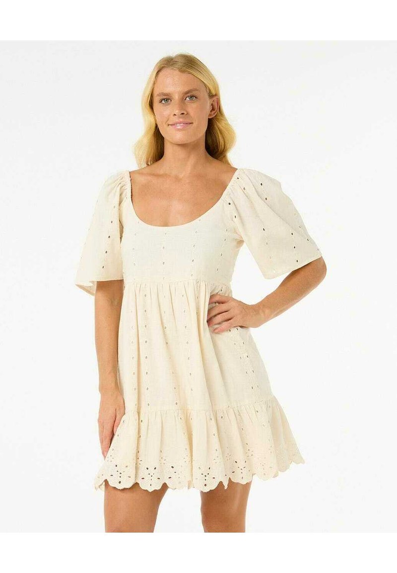 Korte mouwen, crème jurk van lichtgewicht stof. Heeft een vierkante halslijn, geplooide bodice en kantdetails langs de zoom.