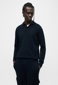 Μπλε ναυτικό πουλόβερ πόλο πλεκτό με μακριά μανίκια, επίπεδη γιακά και πατιλέτα με τρία κουμπιά. Μαλακή υφή, άνετη εφαρμογή, συνδυασμένο με παντελόνι σε ίδιο χρώμα.