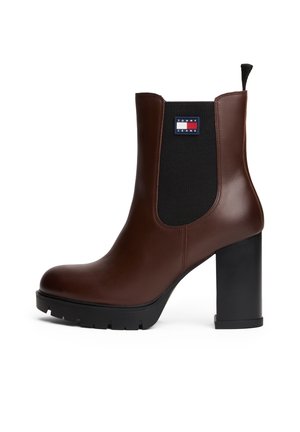 Brązowy skórzany botek z czarnym elastycznym panelem po boku, obcasem typu blok i naszywką z logo Tommy Jeans po bokach.