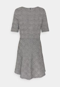 Kleid mit kurzen Ärmeln aus schwarz-weiß kariertem Stoff. Figurnaher Oberteil mit ausgestellt Rock, der diagonale und Gittermuster aufweist. Reißverschluss im Rücken.