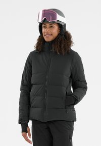 Zwarte gewatteerde jas met een quilted ontwerp, hoge kraag en ritszakken. Gaat gepaard met een helm en skibril, met een glanzende afwerking.