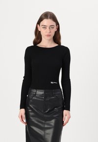 Black ribbed long-sleeve top with a round neckline and a logo detail at the waist, paired with a sleek black leather pencil skirt.
