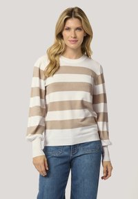 Pull en tricot rayé beige et blanc, avec un col rond, des manches bouffantes longues et des poignets côtelés. Assorti avec un jean bleu à coupe relaxée.