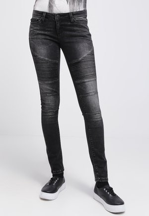 Czarne obcisłe dżinsy z denimu z akcentami o fakturze żeberkowanej na kolanach, z efektem przetarcia i klasycznym fasonem z pięcioma kieszeniami. Zestawione z czarnymi trampkami.