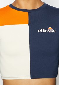 Krótki t-shirt z pomarańczowymi, białymi i granatowymi blokami kolorów. Wykonany z bawełny, ma okrągły dekolt i wyświetla logo ellesse.