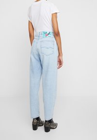 Jeans azzurri a vita alta con una vestibilità rilassata, dotati di un design decorativo nella tasca posteriore e di un'etichetta colorata del brand in vita.