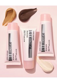 Tre tubetti di trucco Maybelline Perfecter 4-in-1 in confezione rosa, con campioni di crema beige e marrone su uno sfondo chiaro.