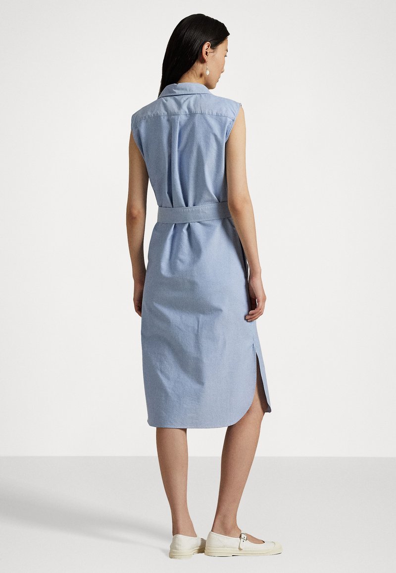 Abito camicia senza maniche di colore azzurro chiaro con vita a cintura, lungo fino al ginocchio e con spacchi laterali, realizzato in un tessuto liscio.