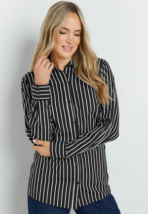 Black and white striped button-up shirt with long sleeves, a collar, and a curved hem. Fabric appears smooth with a fitted design.